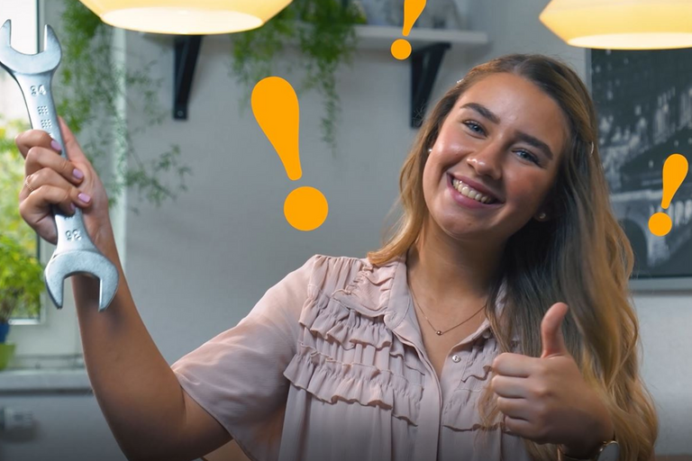 eine junge Frau hält ihren Daumen hoch und einen Maulschlüssel in der anderen Hand, während Ausrufezeichen um ihren Kopf fliegen