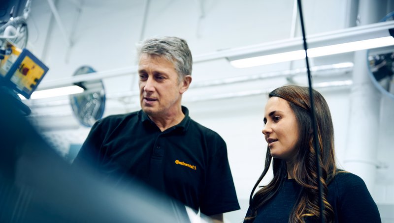 A man and a woman in black poloshirts are looking at something together