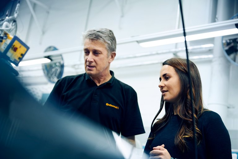 A man and a woman in black poloshirts are looking at something together