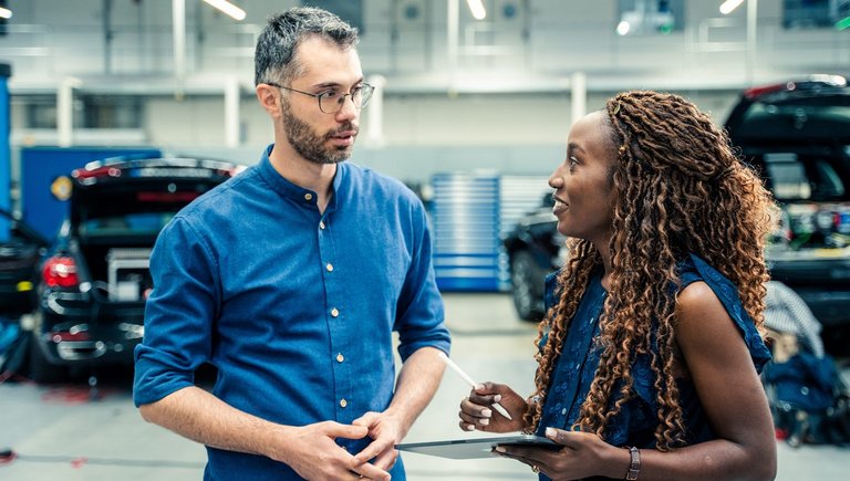A man and a woman stand in a production hall and look at each other